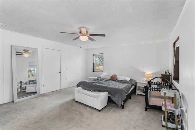 carpeted bedroom with wood walls, a textured ceiling, and ceiling fan