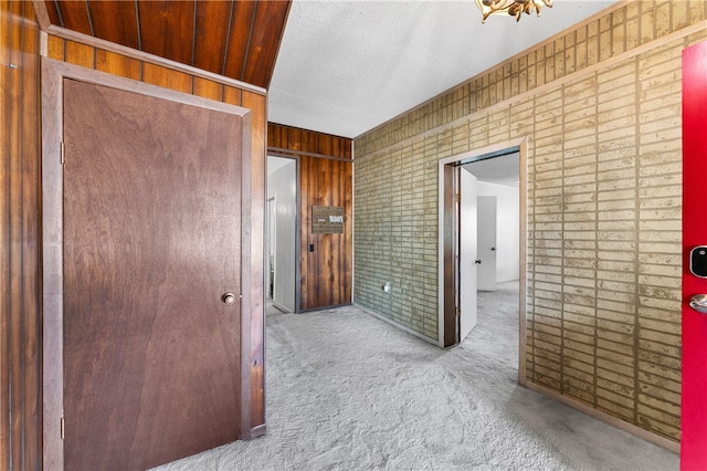 hall with wood walls and light colored carpet