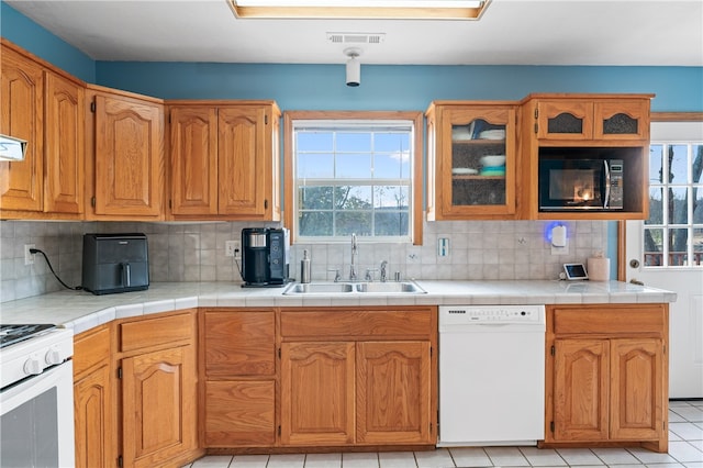 kitchen with sink, decorative backsplash, tile counters, and white appliances