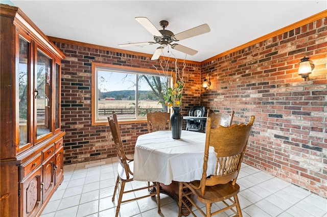 tiled dining space featuring ceiling fan, brick wall, and ornamental molding