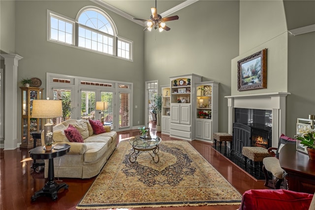 living room featuring a wealth of natural light, a premium fireplace, a high ceiling, and ornamental molding