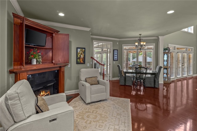 living room with a notable chandelier, crown molding, a tiled fireplace, and hardwood / wood-style flooring