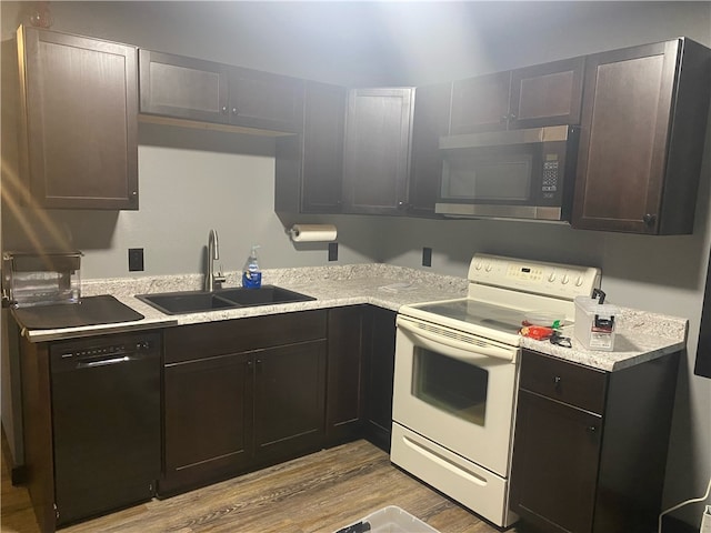 kitchen with black dishwasher, sink, white range with electric cooktop, dark brown cabinetry, and light wood-type flooring