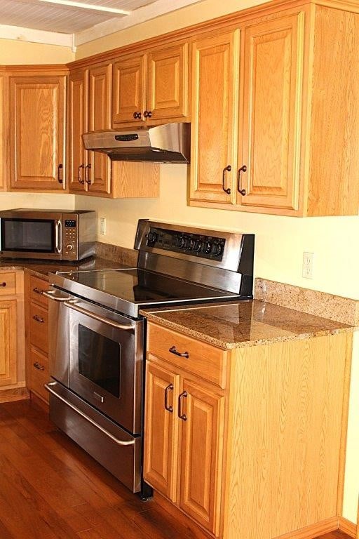 18960 Coppermine Rd, Rogers, AR 72756 - kitchen featuring light stone countertops, under cabinet range hood, stainless steel appliances, dark wood-type flooring, and brown cabinets