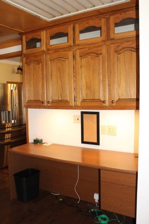 18960 Coppermine Rd, Rogers, AR 72756 - kitchen with stainless steel fridge, brown cabinetry, built in desk, and light countertops