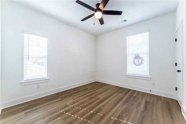 spare room featuring dark hardwood / wood-style flooring, ceiling fan, and plenty of natural light