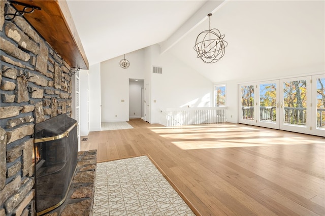 living room featuring a chandelier, high vaulted ceiling, beamed ceiling, a fireplace, and light hardwood / wood-style floors