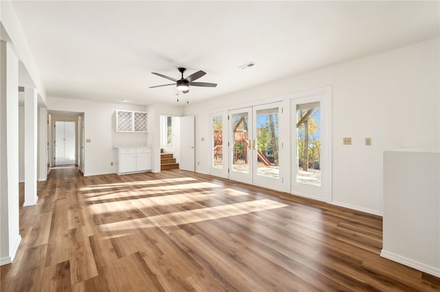 unfurnished living room featuring hardwood / wood-style floors, ceiling fan, and french doors