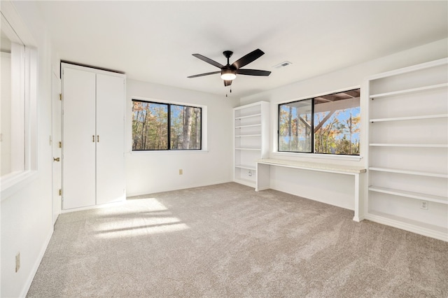 unfurnished bedroom featuring multiple windows, light carpet, and ceiling fan