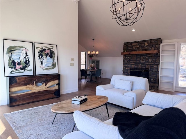 living room with a notable chandelier, wood-type flooring, a fireplace, and high vaulted ceiling