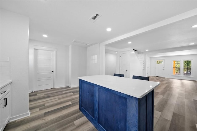 kitchen featuring white cabinets, a kitchen island, and wood-type flooring