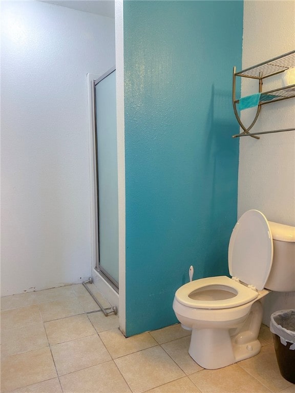 bathroom with toilet, a shower with shower door, and tile patterned flooring