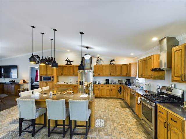 kitchen featuring a kitchen bar, a kitchen island with sink, wall chimney exhaust hood, and appliances with stainless steel finishes