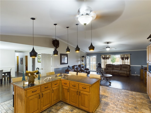 kitchen featuring ornamental molding, ceiling fan, decorative light fixtures, hardwood / wood-style floors, and a kitchen island