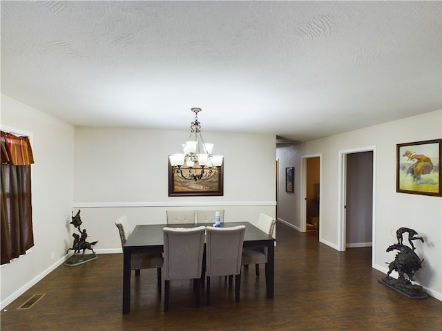 dining space featuring a textured ceiling, an inviting chandelier, and dark wood-type flooring