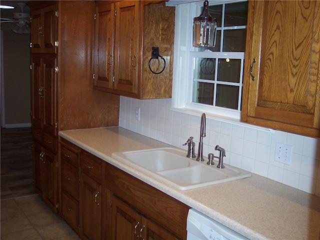 kitchen featuring dark tile patterned flooring, tasteful backsplash, sink, and dishwasher