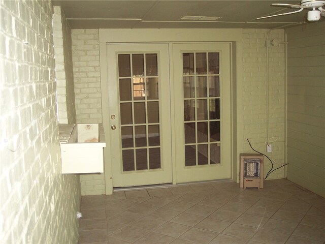 exterior space featuring french doors, light tile patterned flooring, brick wall, and ceiling fan