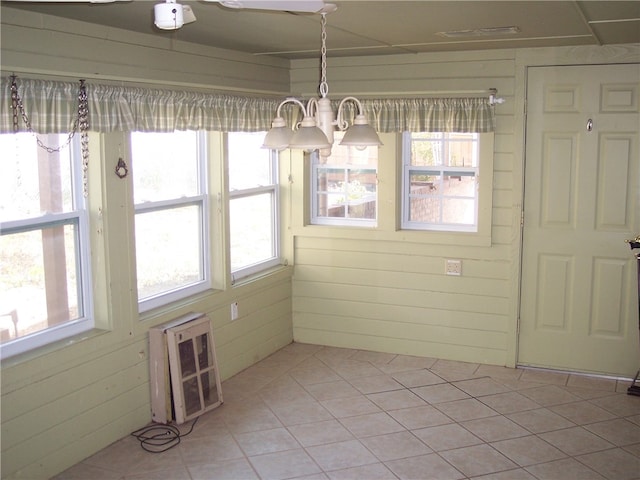 unfurnished dining area with light tile patterned floors, a notable chandelier, heating unit, and wooden walls