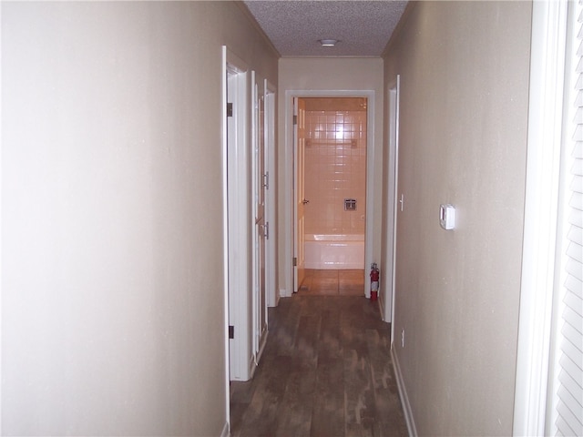 corridor with a textured ceiling and dark hardwood / wood-style floors