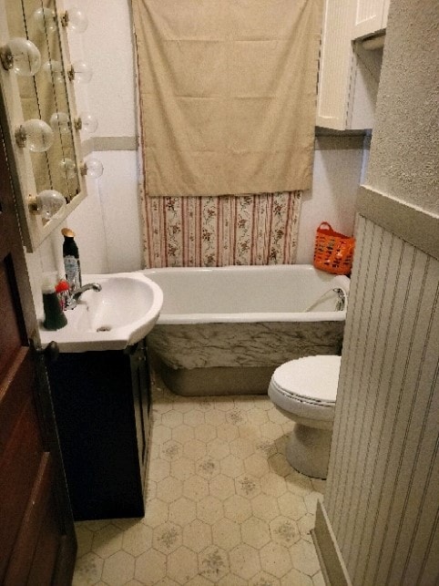 bathroom featuring vanity, toilet, tiled tub, and tile patterned flooring