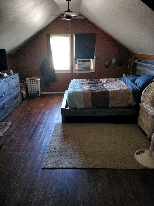 unfurnished bedroom with a textured ceiling, cooling unit, ceiling fan, vaulted ceiling, and dark wood-type flooring