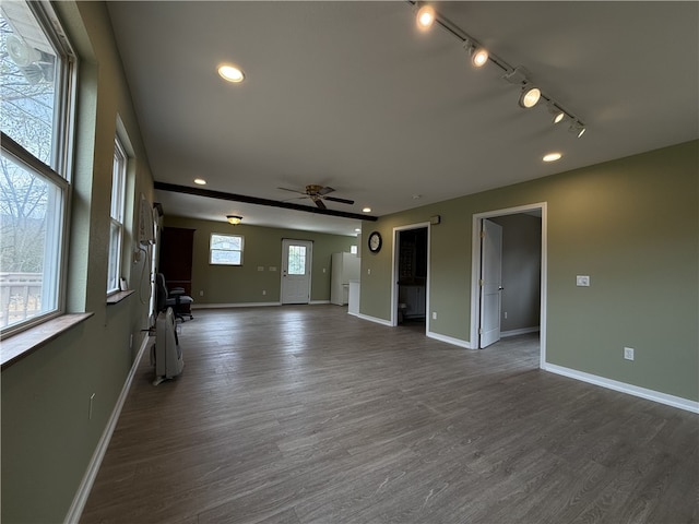 unfurnished living room with dark wood-type flooring, ceiling fan, track lighting, and plenty of natural light