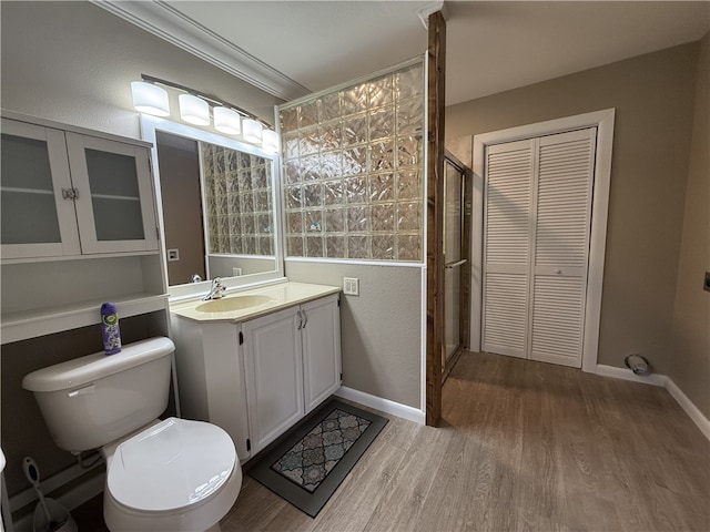 bathroom featuring a shower with door, wood-type flooring, toilet, vanity, and ornamental molding