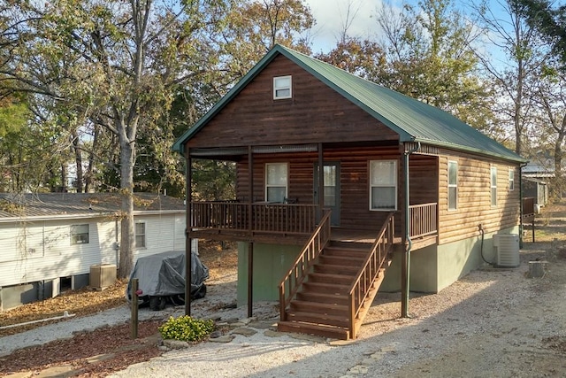 view of front of home featuring log veneer siding, metal roof, covered porch, stairs, and central AC