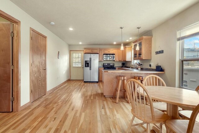 kitchen featuring recessed lighting, stainless steel appliances, a peninsula, light wood finished floors, and glass insert cabinets