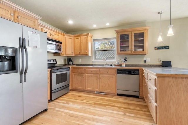 kitchen with a peninsula, light wood finished floors, stainless steel appliances, and a sink