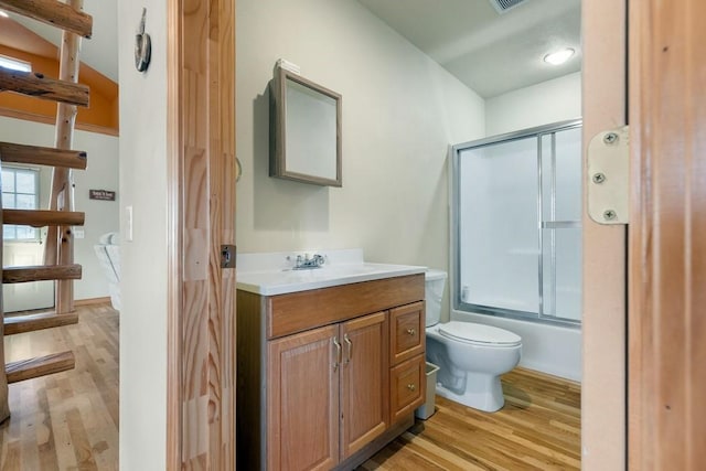 full bath with toilet, shower / bath combination with glass door, wood finished floors, visible vents, and vanity