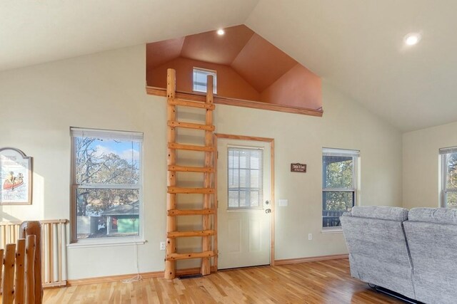 living room with a wealth of natural light, high vaulted ceiling, and light hardwood / wood-style floors