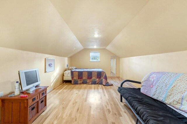 bedroom with vaulted ceiling and light wood-type flooring