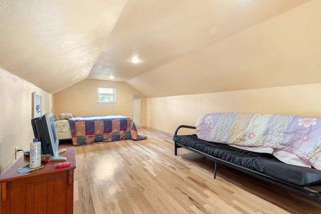 bedroom featuring vaulted ceiling, a textured ceiling, and light wood finished floors