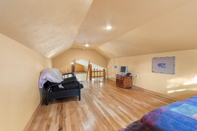 bedroom with vaulted ceiling, a textured ceiling, baseboards, and wood finished floors