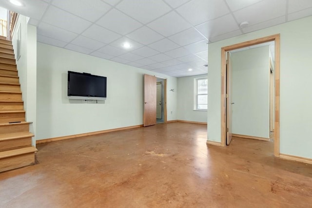 basement with stairs, a paneled ceiling, and baseboards