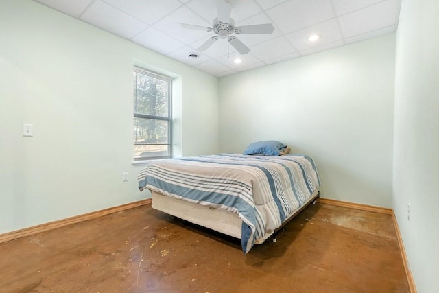 bedroom featuring concrete flooring, a drop ceiling, visible vents, and baseboards