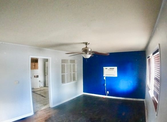 unfurnished room with ceiling fan, a textured ceiling, and a wall mounted air conditioner