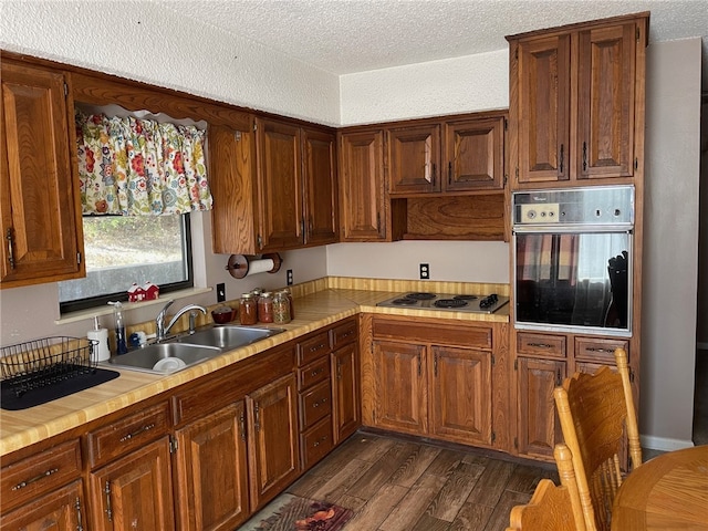 kitchen featuring cooktop, sink, a textured ceiling, dark hardwood / wood-style flooring, and oven