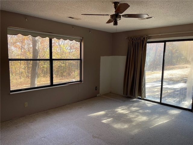 carpeted spare room featuring ceiling fan and a textured ceiling