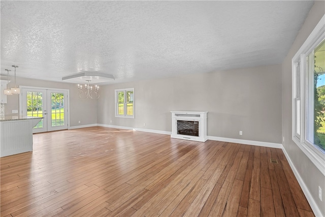 unfurnished living room featuring light hardwood / wood-style flooring, a textured ceiling, and plenty of natural light