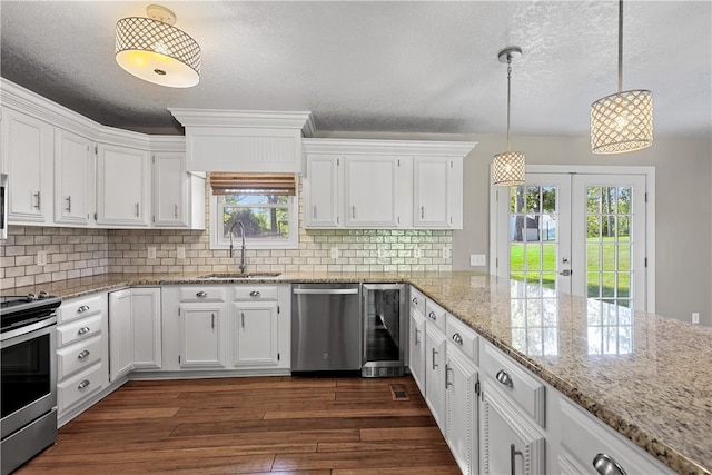 kitchen with dark wood-type flooring, appliances with stainless steel finishes, hanging light fixtures, and white cabinets