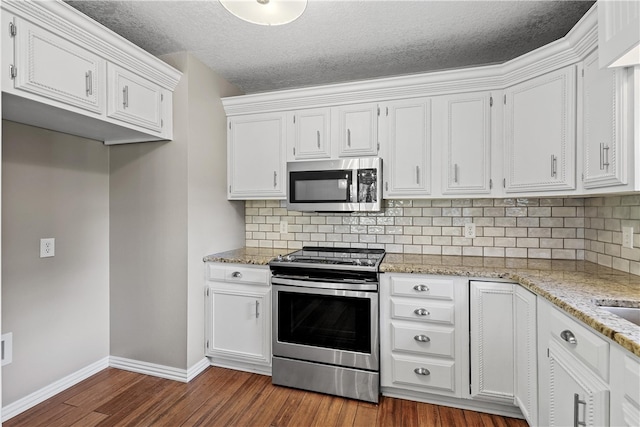 kitchen with decorative backsplash, dark hardwood / wood-style floors, white cabinetry, appliances with stainless steel finishes, and a textured ceiling