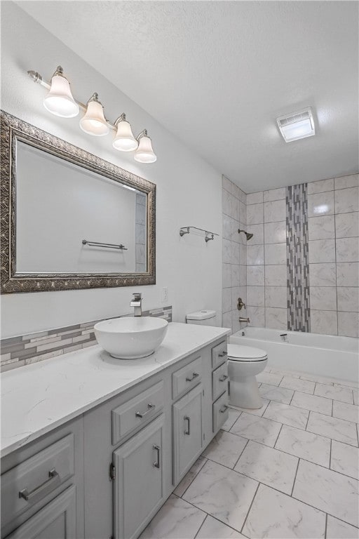 full bathroom with vanity, toilet, a textured ceiling, and tiled shower / bath