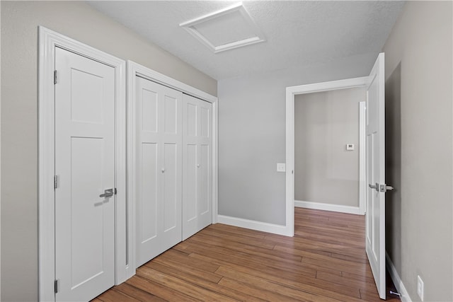 unfurnished bedroom featuring a closet, wood-type flooring, and a textured ceiling