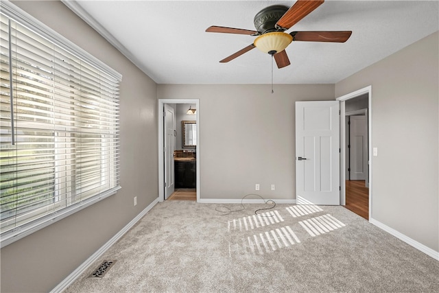 unfurnished bedroom featuring light carpet, ensuite bathroom, and ceiling fan