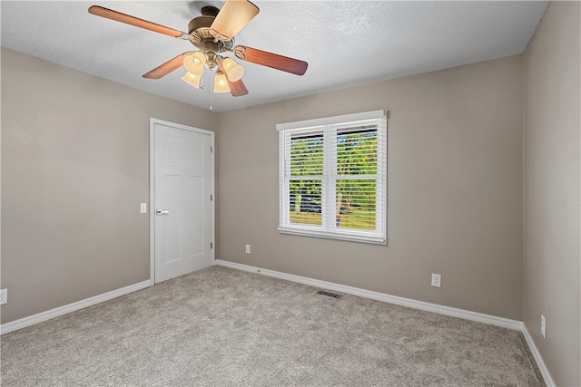 empty room featuring light carpet, a textured ceiling, and ceiling fan