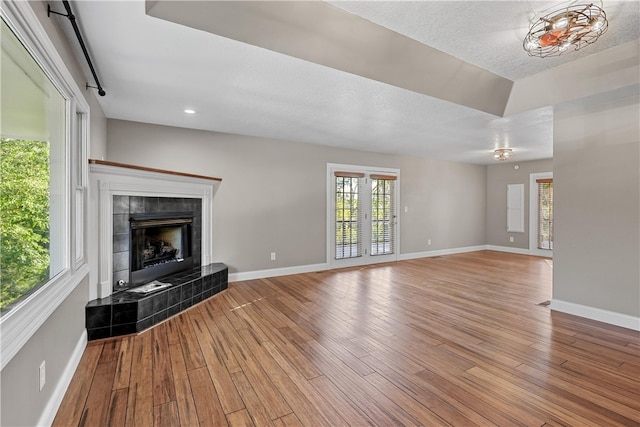 unfurnished living room featuring a tile fireplace, a textured ceiling, and light wood-type flooring