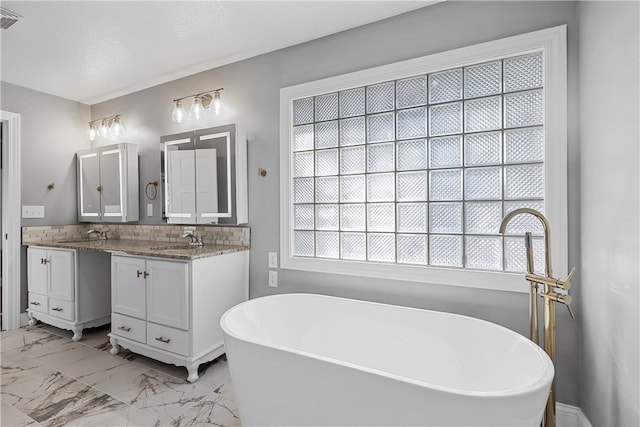 bathroom featuring vanity, a tub to relax in, and a textured ceiling