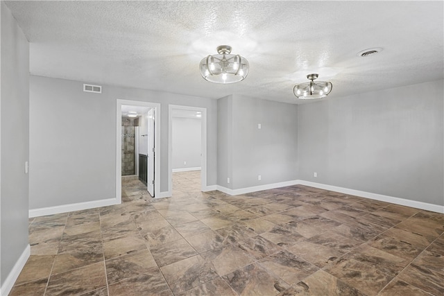 unfurnished room featuring a notable chandelier and a textured ceiling